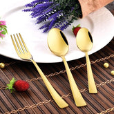 Elegant gold flatware set beside white plate, decorated with strawberries, flowers, and lavender arrangement.